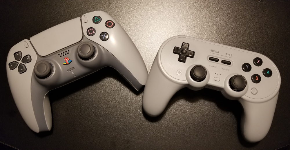 A PS5 Controller color themed after the PS1 next to 8bitdo's Pro 2 controller.